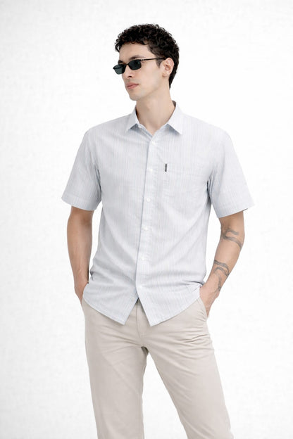 Man wearing a light gray short-sleeve shirt and beige pants on a white background