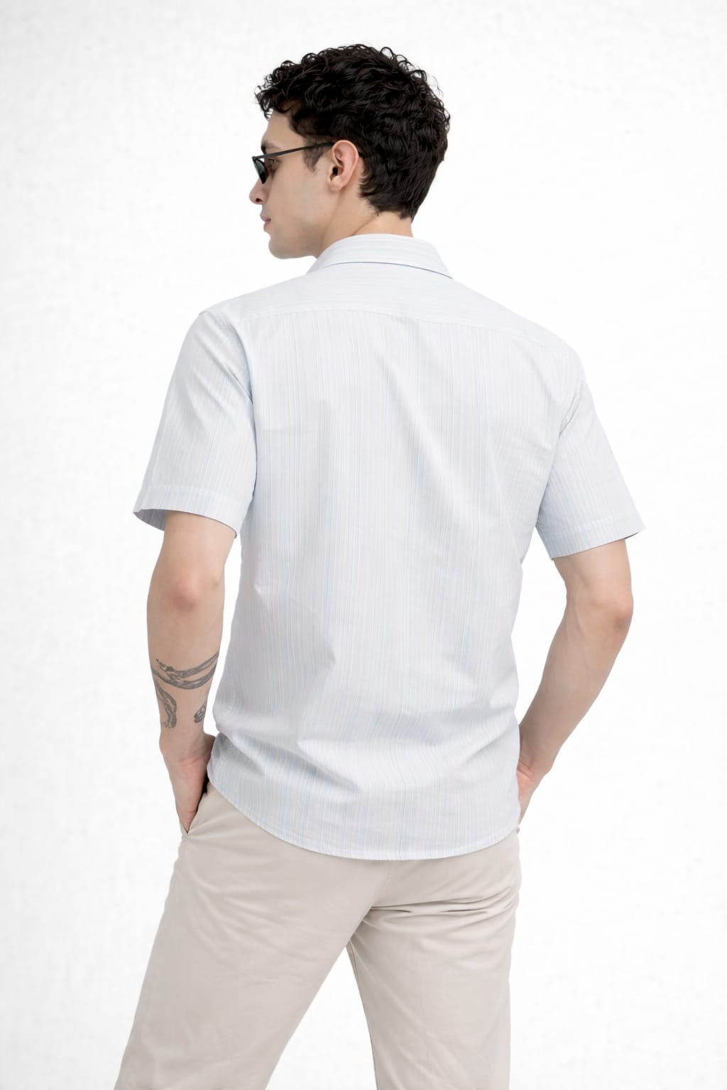Man wearing a white polo shirt and beige pants on a white background
