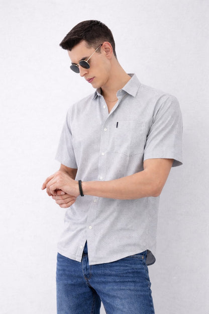 Man wearing a light gray short-sleeve shirt and blue jeans on a white background