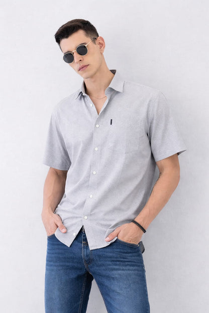 Man wearing a light gray short-sleeve shirt and blue jeans against a white background