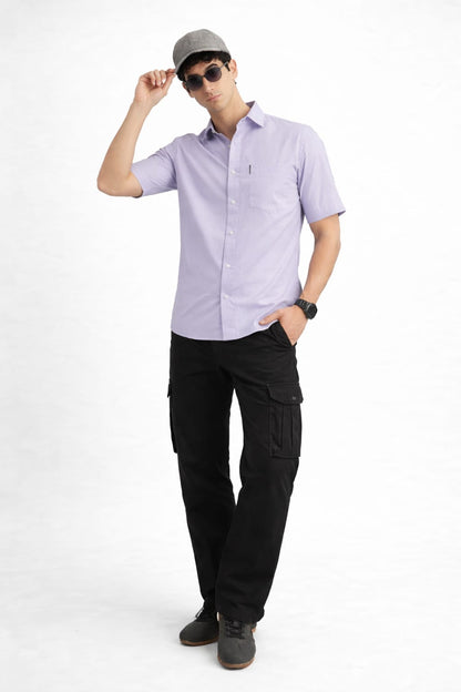 Man wearing a light purple shirt, black pants, and a cap on a white background