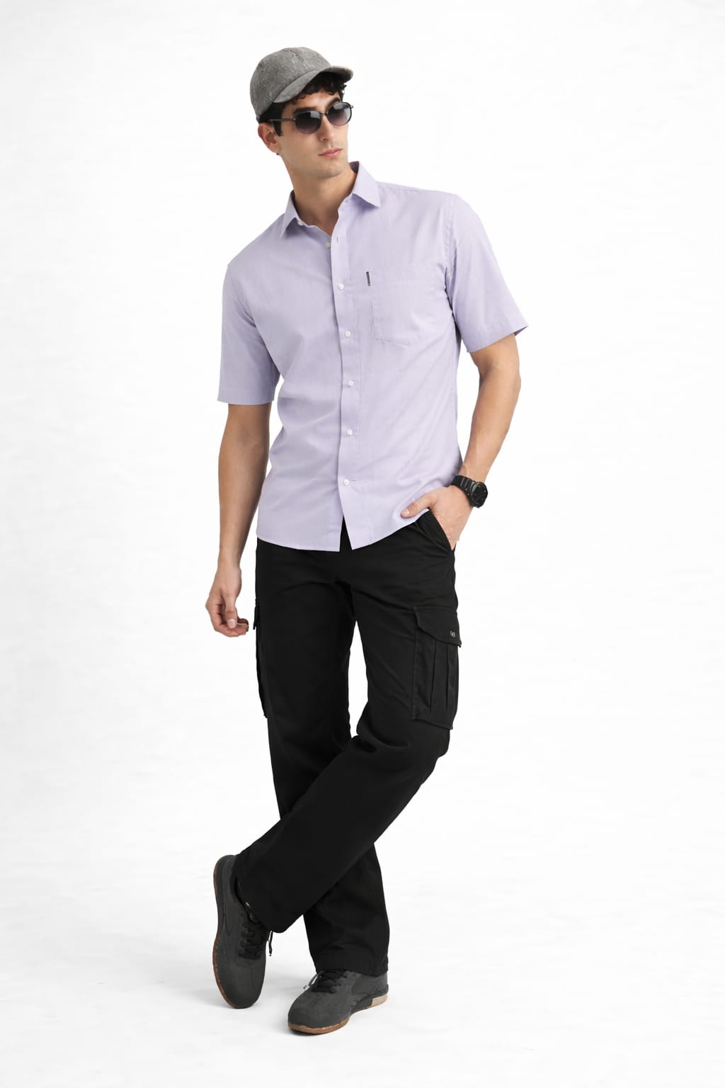 Man wearing a light purple button-up shirt, black pants, and a cap on a white background