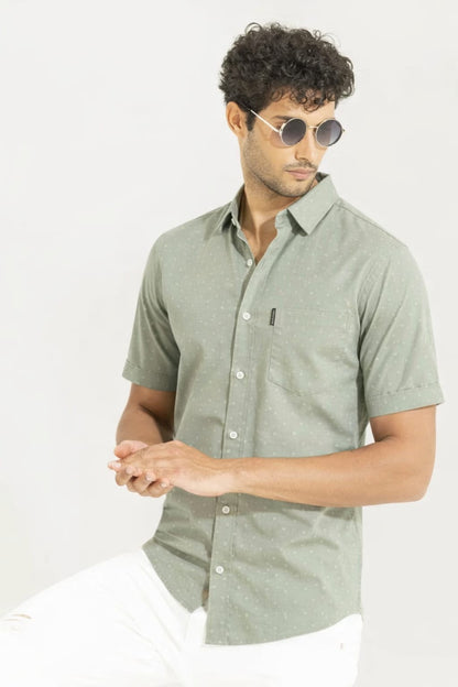 Man wearing a light green button-up shirt with short sleeves on a white background