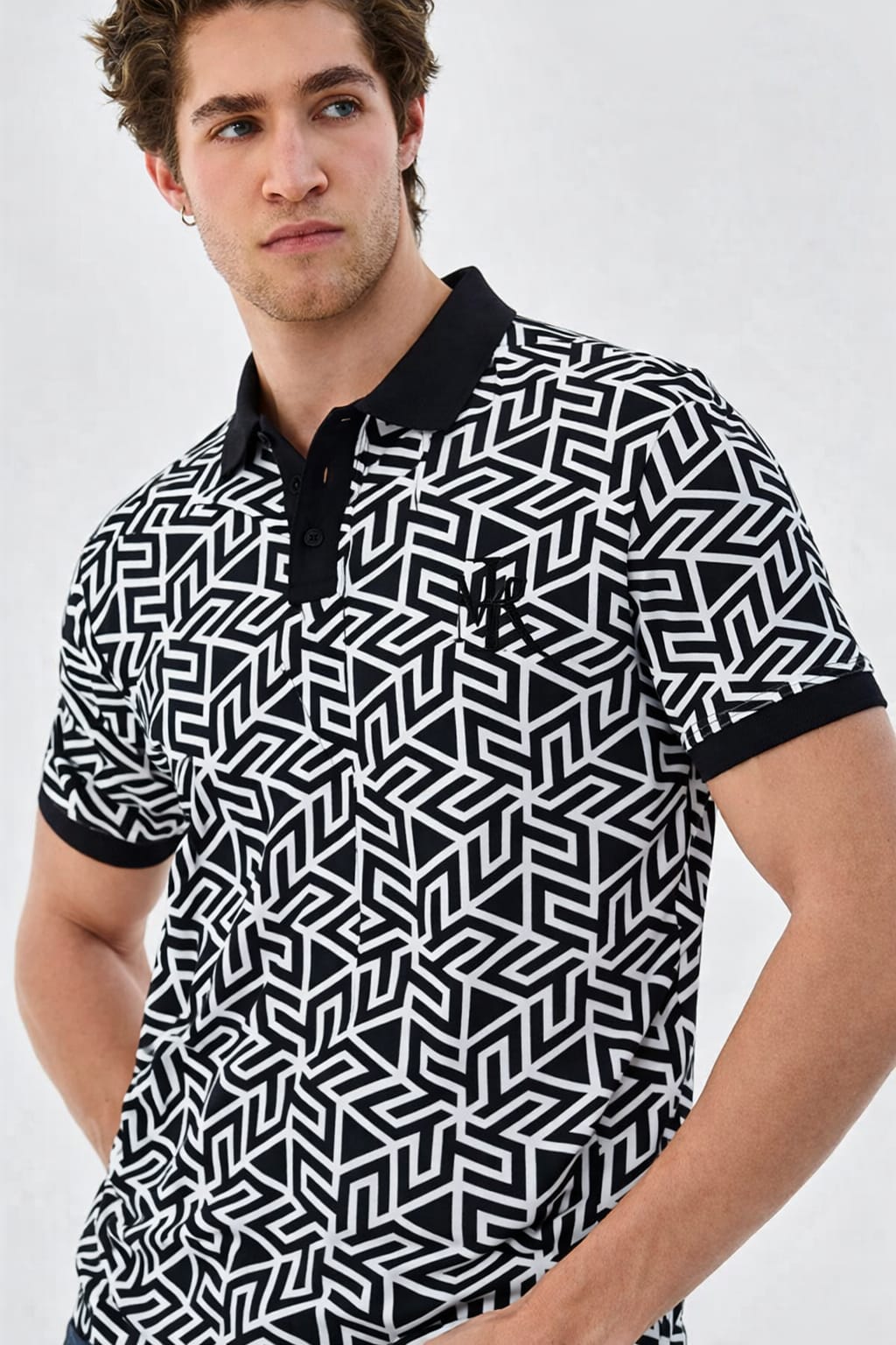 Man wearing a black and white geometric patterned polo shirt on a plain background